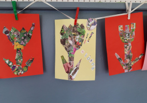 Na tasiemce wiszą trzy prace plastyczne przypięte spinaczami zrobione na kolorowym kartonie, przedstawiające trzy krokusy wykonane techniką kolażu.